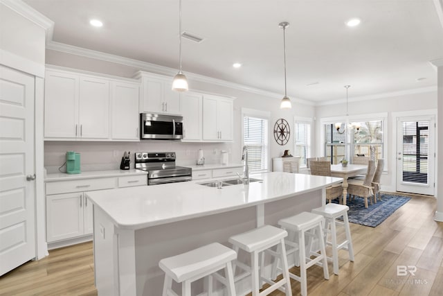 kitchen featuring visible vents, light wood-style flooring, appliances with stainless steel finishes, crown molding, and a sink