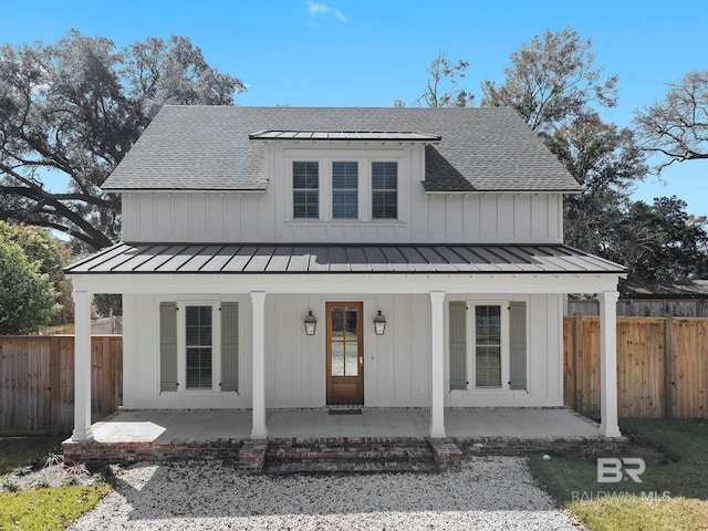 modern farmhouse style home featuring metal roof, roof with shingles, a standing seam roof, and fence