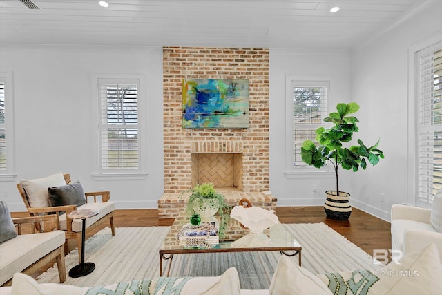 living room with baseboards, ornamental molding, wood finished floors, a fireplace, and recessed lighting