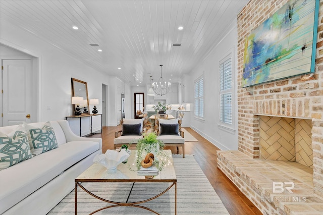 living area with a chandelier, wooden ceiling, a fireplace, and wood finished floors