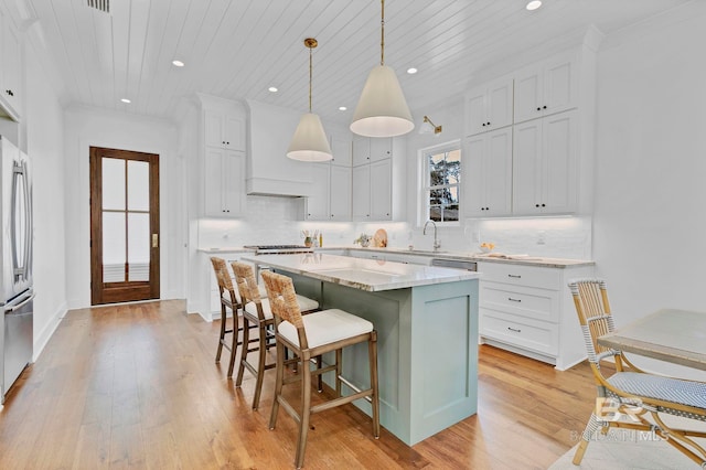 kitchen with wood ceiling, white cabinetry, a kitchen island, and custom exhaust hood