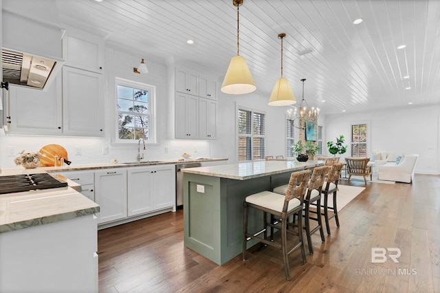 kitchen with a center island, white cabinets, a sink, and light stone countertops