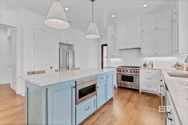 kitchen featuring appliances with stainless steel finishes, custom exhaust hood, light wood-style flooring, and white cabinets