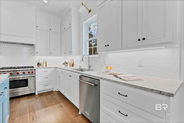 kitchen with wood finished floors, a sink, white cabinetry, appliances with stainless steel finishes, and tasteful backsplash