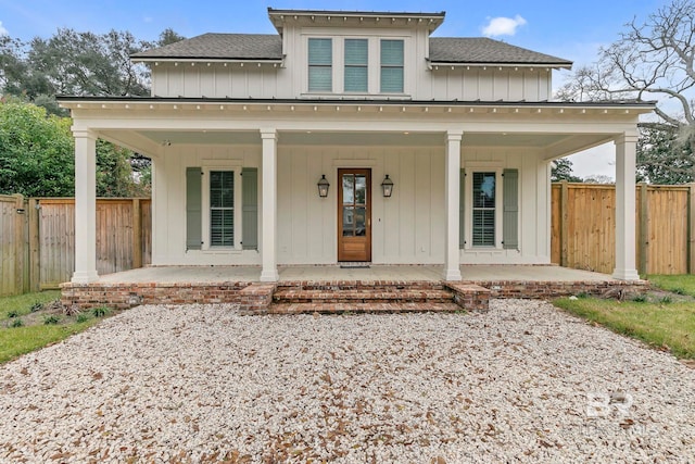 view of front of house featuring fence, board and batten siding, and roof with shingles