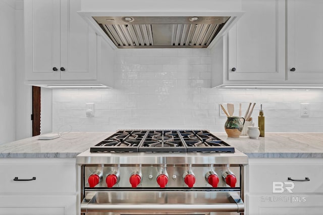 kitchen featuring range hood, high end stainless steel range oven, backsplash, white cabinets, and light stone countertops