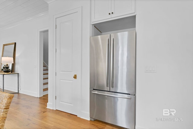 kitchen with light wood-style floors, freestanding refrigerator, white cabinets, and baseboards