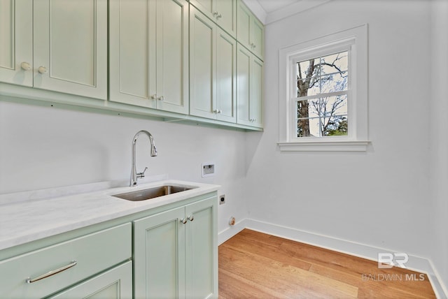 laundry room featuring washer hookup, light wood finished floors, cabinet space, a sink, and baseboards