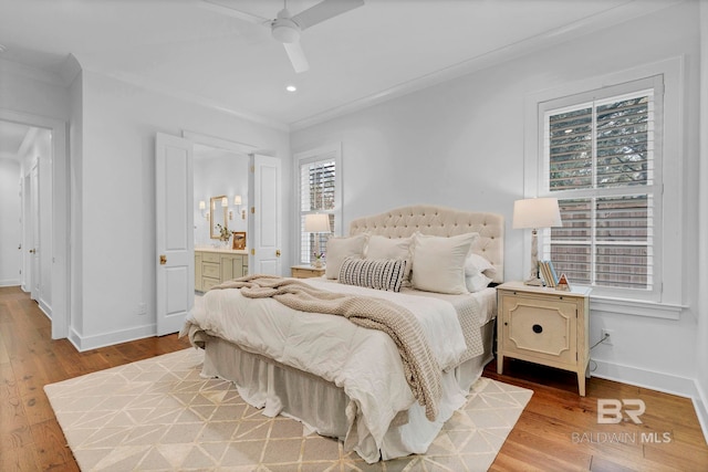 bedroom with ornamental molding, ensuite bath, baseboards, and wood finished floors