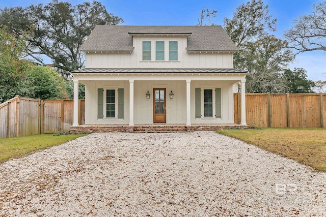 modern inspired farmhouse with covered porch, roof with shingles, a standing seam roof, and fence