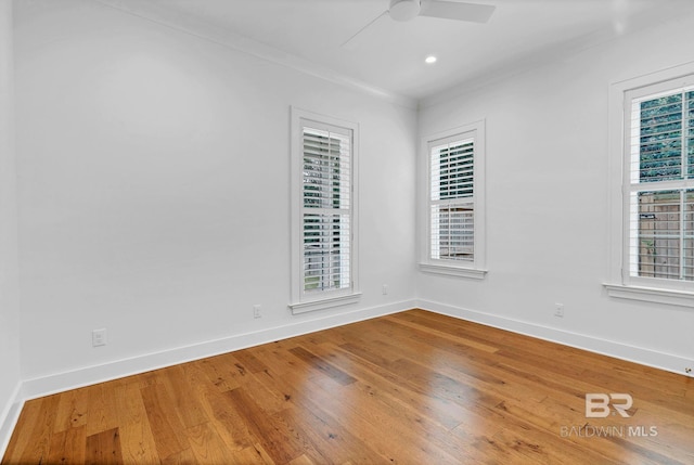 unfurnished room with a healthy amount of sunlight, crown molding, baseboards, and hardwood / wood-style flooring