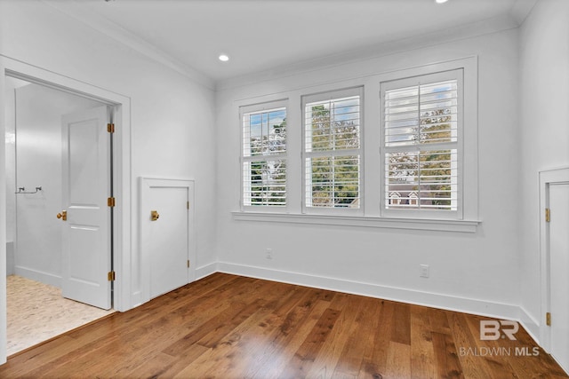 spare room featuring baseboards, recessed lighting, wood-type flooring, and crown molding