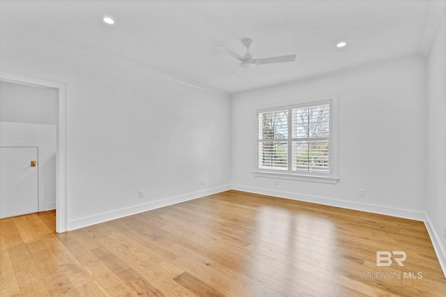 spare room featuring baseboards, light wood-style floors, a ceiling fan, and crown molding