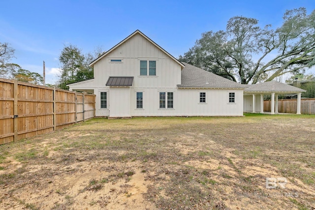 rear view of property featuring a yard, a shingled roof, board and batten siding, and fence private yard