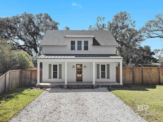 modern farmhouse featuring a shingled roof, a fenced backyard, a standing seam roof, a porch, and a front yard