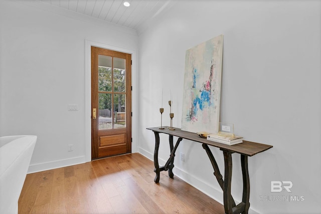 entryway featuring baseboards, crown molding, and light wood finished floors