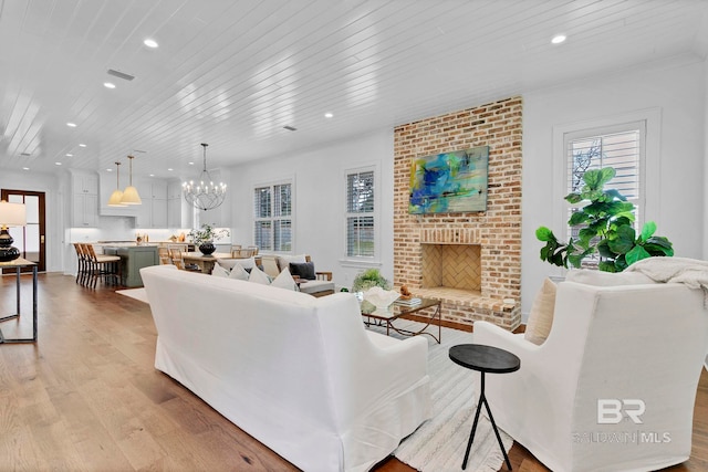 living area with wood ceiling, light wood-type flooring, a brick fireplace, a chandelier, and recessed lighting