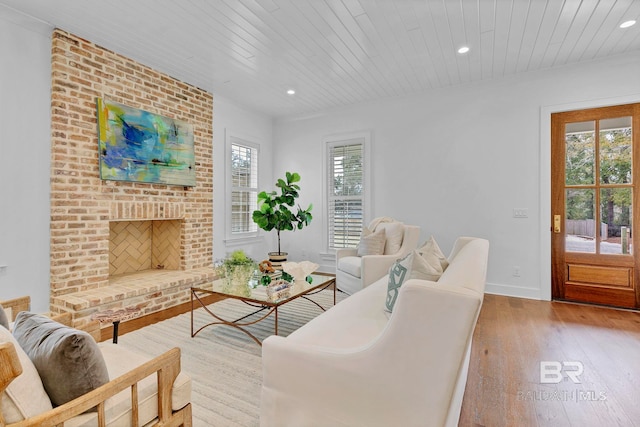 living area with hardwood / wood-style floors, a fireplace, wood ceiling, and a healthy amount of sunlight