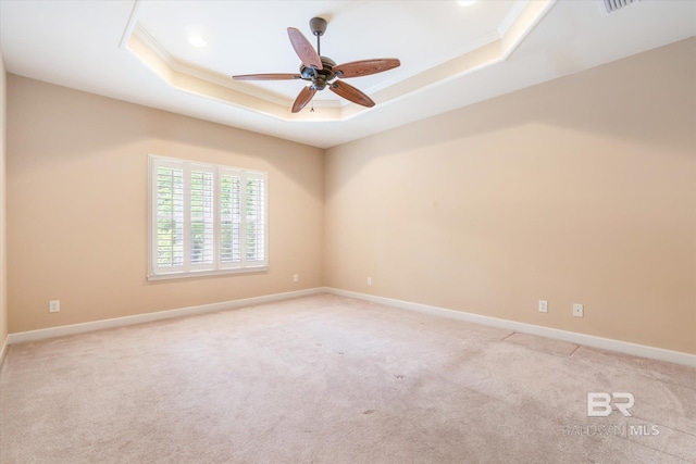 unfurnished room featuring light carpet, a tray ceiling, ceiling fan, and ornamental molding