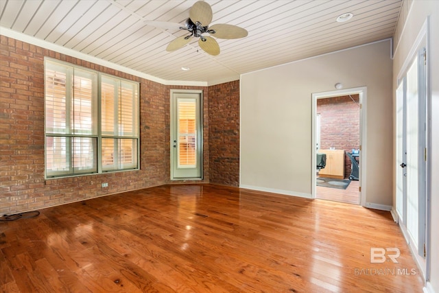 unfurnished room featuring ceiling fan, wood ceiling, ornamental molding, brick wall, and light hardwood / wood-style floors