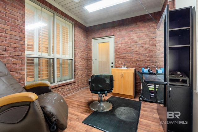 office area featuring ornamental molding, light wood-type flooring, and brick wall