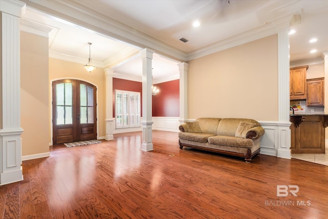 living room with decorative columns, ornamental molding, french doors, and hardwood / wood-style flooring