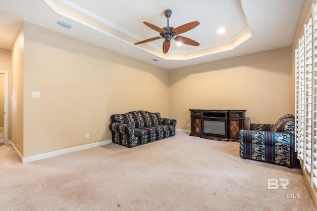 sitting room with carpet, a tray ceiling, and ceiling fan