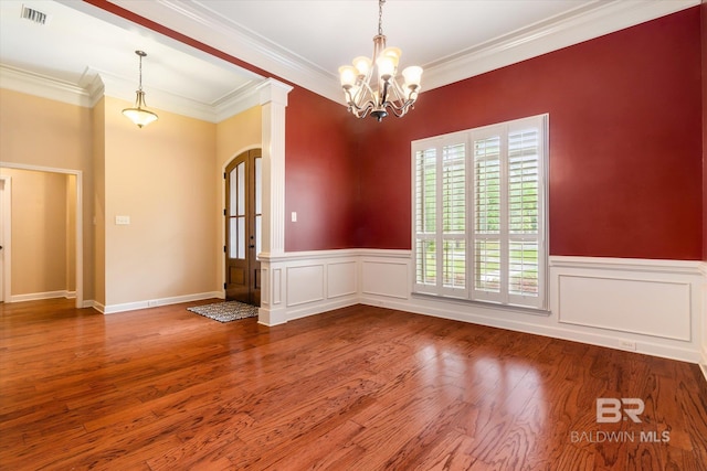 unfurnished room featuring hardwood / wood-style floors, ornamental molding, and a chandelier