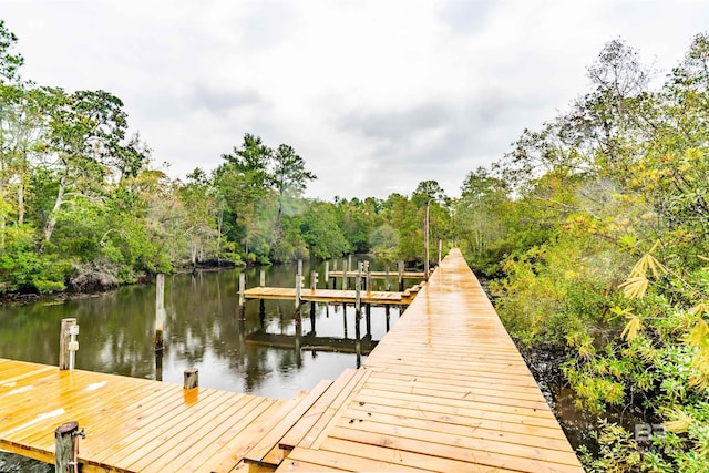 view of dock with a water view and a wooded view