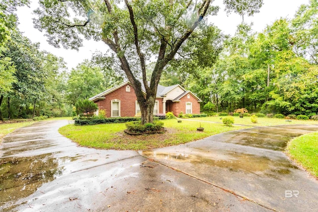 view of side of home featuring a yard, brick siding, and driveway