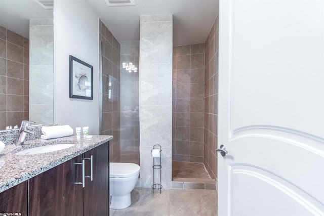 bathroom featuring tile flooring, toilet, vanity, and a tile shower