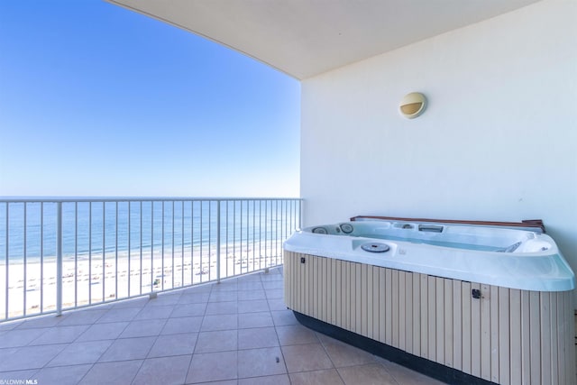 balcony featuring a water view, a view of the beach, and a hot tub