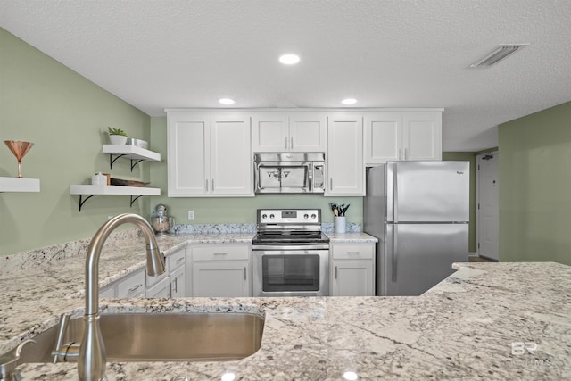 375 Beach Club Trl Unit B404, Gulf Shores, AL 36542 - kitchen with appliances with stainless steel finishes, a sink, open shelves, white cabinetry, and a textured ceiling