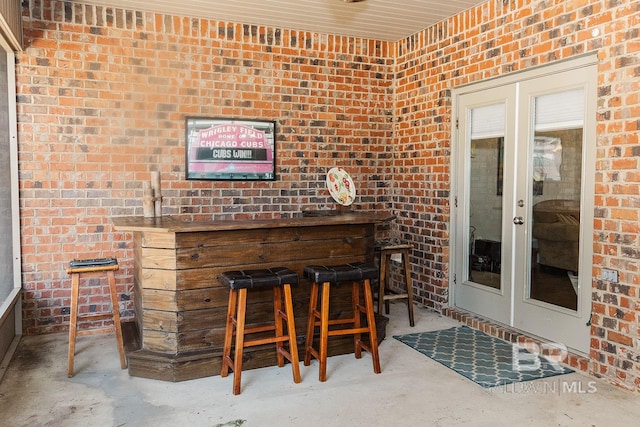 bar featuring concrete floors, brick wall, and french doors