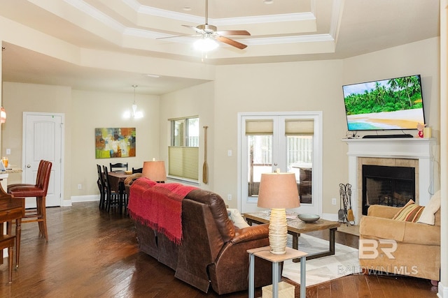 living room featuring ceiling fan, a raised ceiling, dark wood-type flooring, and crown molding