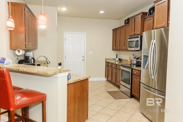 kitchen featuring pendant lighting, kitchen peninsula, a kitchen breakfast bar, stainless steel appliances, and light stone countertops