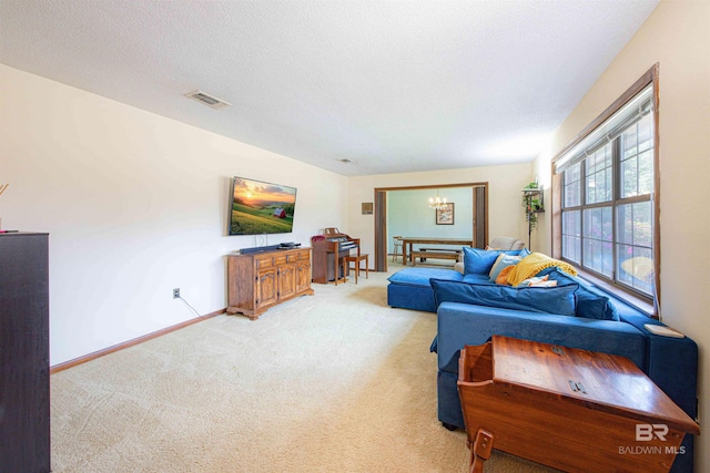 living room with visible vents, baseboards, an inviting chandelier, a textured ceiling, and light colored carpet