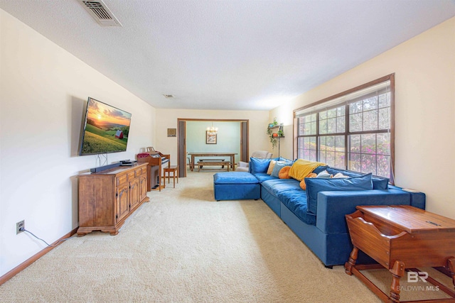 living area with a notable chandelier, light colored carpet, visible vents, and a textured ceiling