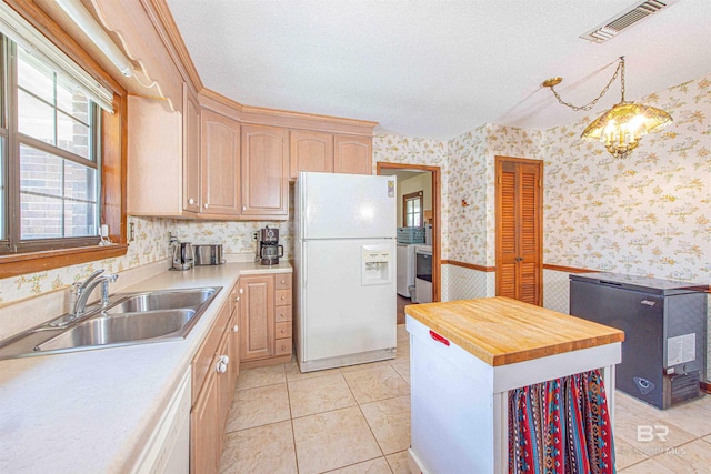 kitchen with wallpapered walls, white appliances, a textured ceiling, and a sink