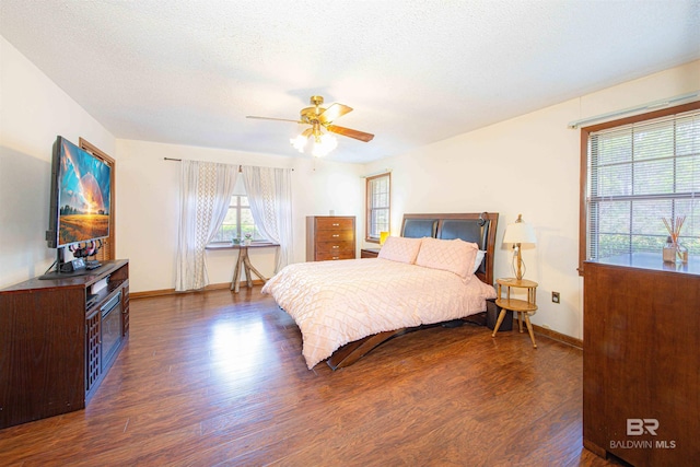 bedroom featuring dark wood-style floors, a textured ceiling, baseboards, and a ceiling fan