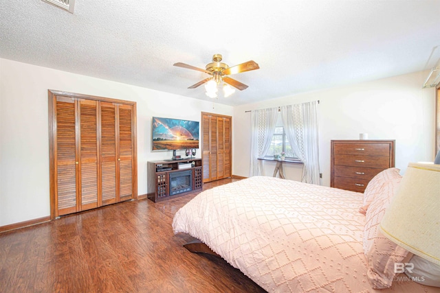 bedroom featuring baseboards, wood finished floors, multiple closets, and a textured ceiling