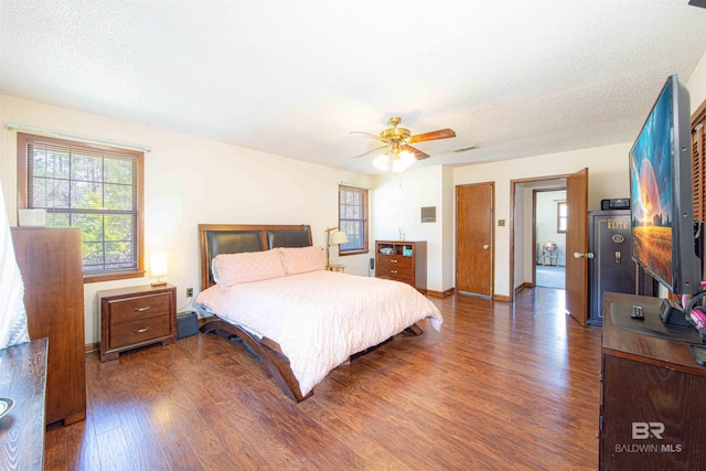 bedroom featuring ceiling fan, a textured ceiling, baseboards, and dark wood-style flooring