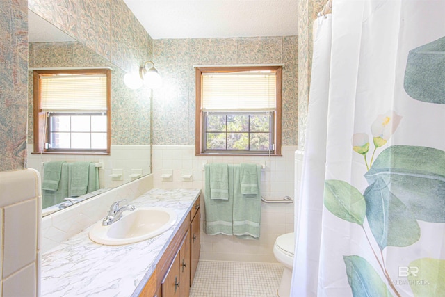 bathroom with a wainscoted wall, tile walls, a healthy amount of sunlight, and wallpapered walls