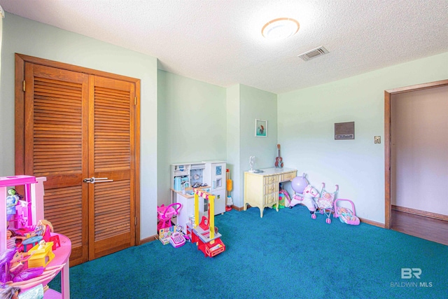 recreation room with visible vents, a textured ceiling, baseboards, and carpet floors