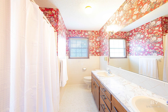 bathroom with wainscoting, wallpapered walls, and a sink