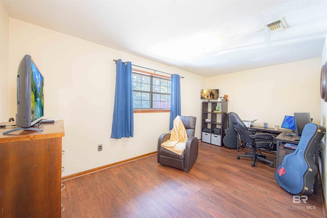 office space with wood finished floors, visible vents, and baseboards