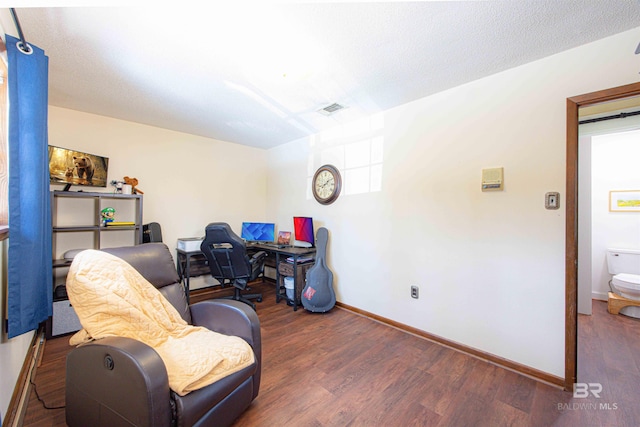 office with visible vents, a textured ceiling, baseboards, and wood finished floors