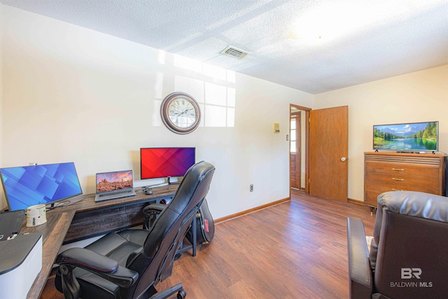 office with visible vents, baseboards, a textured ceiling, and wood finished floors