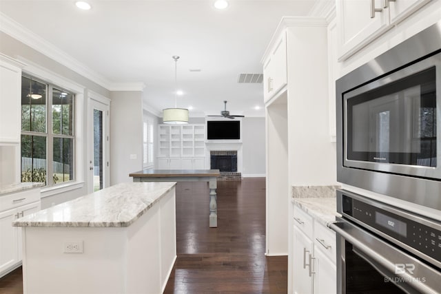 kitchen featuring stainless steel appliances, light stone countertops, a center island, and white cabinets