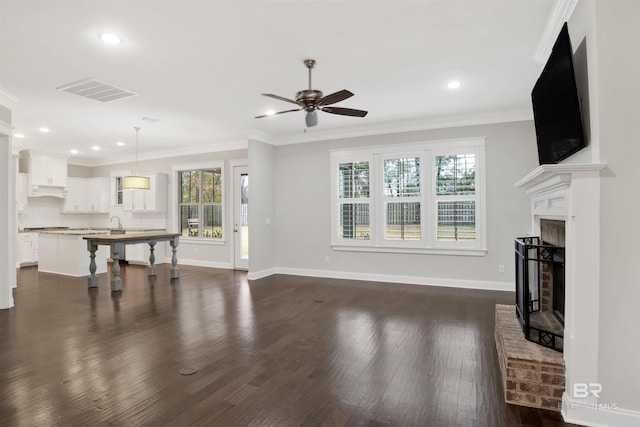 living room with dark hardwood / wood-style flooring, a brick fireplace, ornamental molding, and a healthy amount of sunlight